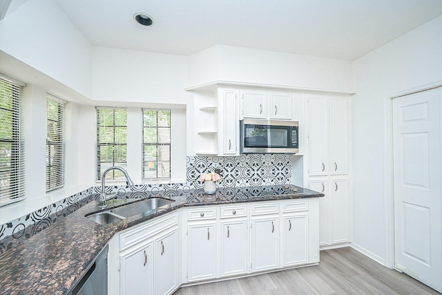 31 Silent Brook Pl, The Woodlands, TX 77381 - kitchen with stainless steel microwave, a sink, dark stone countertops, light wood-style flooring, and white cabinets