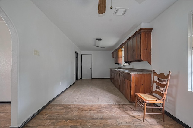 423 Gammon Dr, Houston, TX 77022 - kitchen with ceiling fan, arched walkways, light wood-type flooring, and dark countertops
