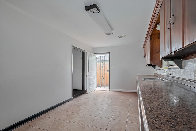423 Gammon Dr, Houston, TX 77022 - kitchen featuring a sink, dark countertops, baseboards, and light tile patterned flooring