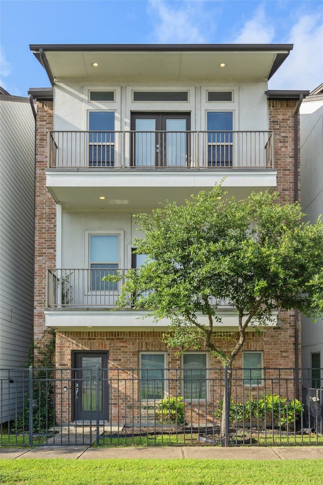727 Schwartz St, Houston, TX 77020 - view of front of property featuring a balcony, stucco siding, a fenced front yard, and brick siding