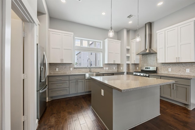727 Schwartz St, Houston, TX 77020 - kitchen featuring wall chimney range hood, appliances with stainless steel finishes, gray cabinets, a kitchen island, and dark wood-style floors