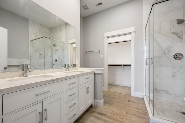 727 Schwartz St, Houston, TX 77020 - bathroom with a marble finish shower, double vanity, wood finished floors, and a walk in closet
