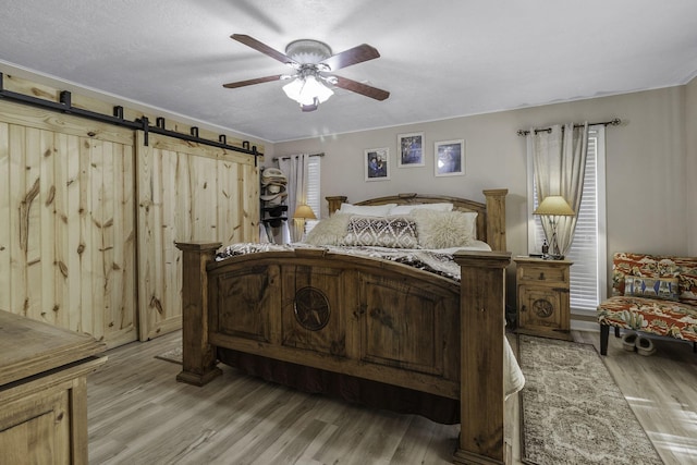 6462 US Highway 190 E, Livingston, TX 77351 - bedroom with light wood-style flooring, a barn door, and ceiling fan
