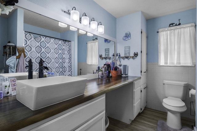6462 US Highway 190 E, Livingston, TX 77351 - full bathroom featuring wood finished floors, vanity, toilet, tile walls, and wainscoting