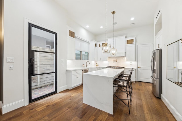 540 W 26th St Unit B, Houston, TX 77008 - kitchen with appliances with stainless steel finishes, a breakfast bar, a kitchen island, backsplash, and white cabinetry