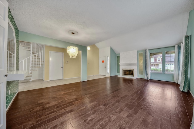 4214 Hambledon Village Dr, Houston, TX 77014 - unfurnished living room with a chandelier, wood finished floors, a brick fireplace, lofted ceiling, and baseboards