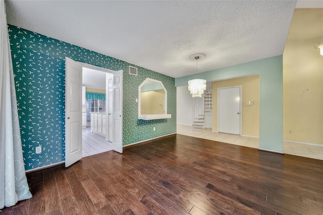 4214 Hambledon Village Dr, Houston, TX 77014 - empty room featuring hardwood / wood-style floors, a textured ceiling, stairway, a chandelier, and baseboards