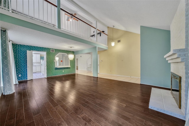 4214 Hambledon Village Dr, Houston, TX 77014 - unfurnished living room with wallpapered walls, baseboards, a brick fireplace, wood finished floors, and high vaulted ceiling
