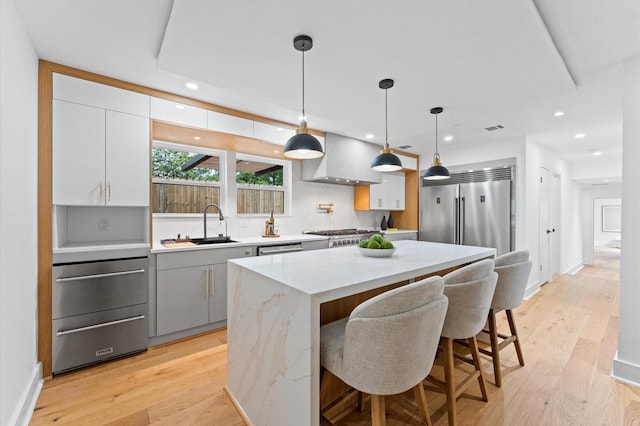 1100 S Shepherd Dr, Houston, TX 77019 - kitchen with ventilation hood, appliances with stainless steel finishes, light wood-style flooring, a center island, and recessed lighting