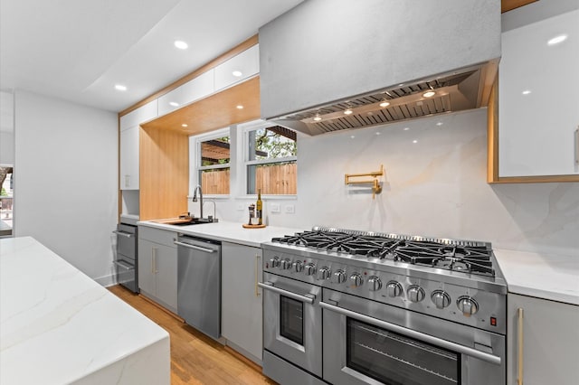 1100 S Shepherd Dr, Houston, TX 77019 - kitchen featuring stainless steel appliances, wall chimney exhaust hood, gray cabinetry, light wood-type flooring, and recessed lighting