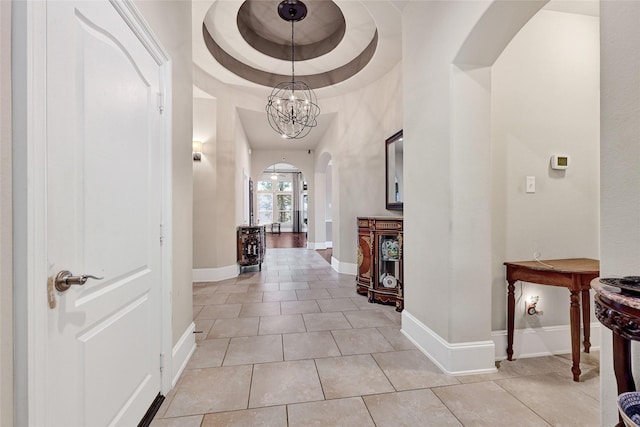 21115 Magnolia Hollow Ln, Richmond, TX 77407 - hallway with arched walkways, light tile patterned floors, baseboards, a raised ceiling, and a chandelier