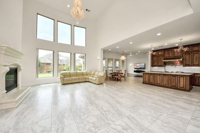 18111 Dockside Landing Dr, Cypress, TX 77433 - living room with a chandelier, recessed lighting, a glass covered fireplace, a high ceiling, and light marble finish flooring
