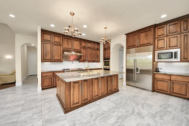 18111 Dockside Landing Dr, Cypress, TX 77433 - kitchen with built in appliances, arched walkways, under cabinet range hood, light marble finish flooring, and a chandelier