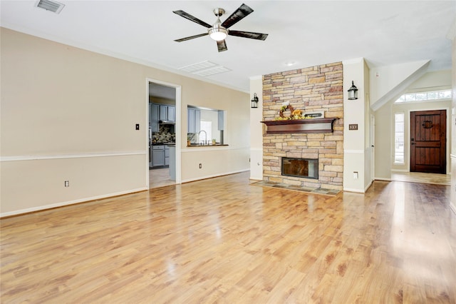 5208 Jolie Dr, Pearland, TX 77584 - unfurnished living room with a ceiling fan, light wood-type flooring, ornamental molding, a stone fireplace, and baseboards