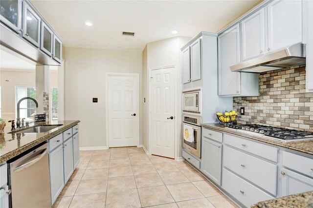 5208 Jolie Dr, Pearland, TX 77584 - kitchen with appliances with stainless steel finishes, under cabinet range hood, a sink, decorative backsplash, and dark stone countertops