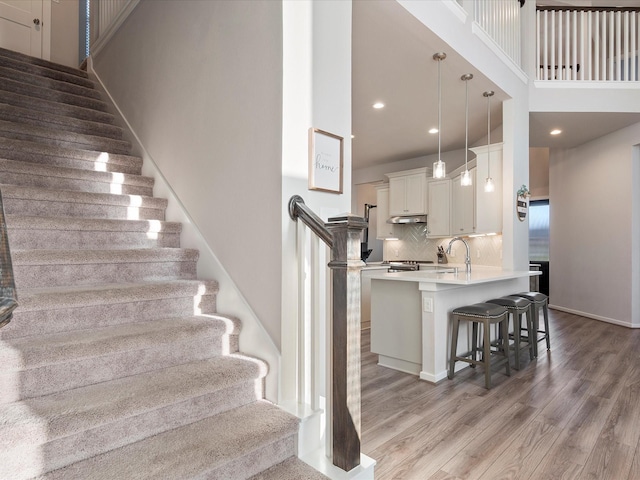 9715 Migrant Hawker Ct, Conroe, TX 77385 - staircase with wood finished floors, recessed lighting, a towering ceiling, and baseboards