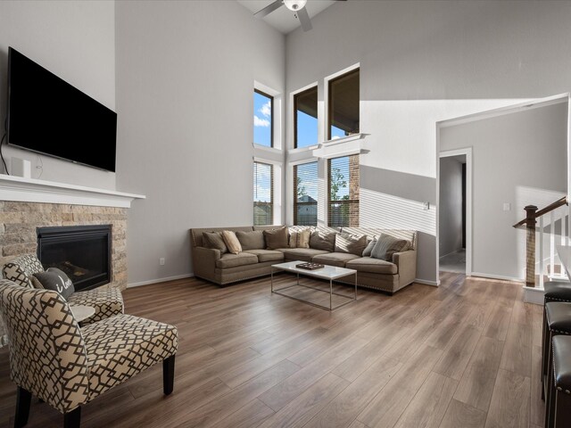 9715 Migrant Hawker Ct, Conroe, TX 77385 - living area featuring a high ceiling, ceiling fan, wood finished floors, a stone fireplace, and stairway