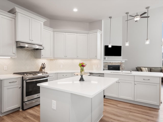 9715 Migrant Hawker Ct, Conroe, TX 77385 - kitchen featuring stainless steel gas stove, under cabinet range hood, a sink, a peninsula, and light countertops