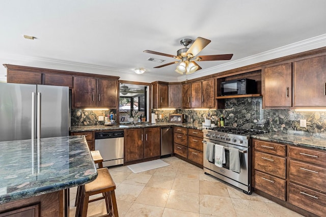 36 Lakeview Dr, Galveston, TX 77551 - kitchen with appliances with stainless steel finishes, ceiling fan, crown molding, tasteful backsplash, and dark stone counters