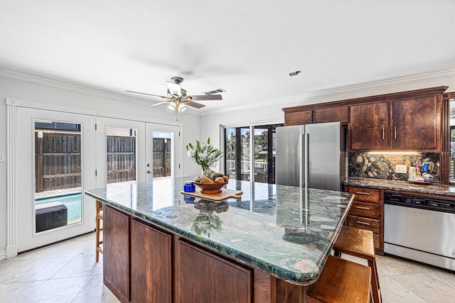 36 Lakeview Dr, Galveston, TX 77551 - kitchen featuring appliances with stainless steel finishes, french doors, a kitchen breakfast bar, dark stone countertops, and decorative backsplash