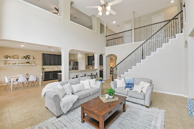 19538 Salt Grass Meadow Dr, Cypress, TX 77433 - living room featuring arched walkways, ceiling fan, light tile patterned floors, stairway, and a high ceiling