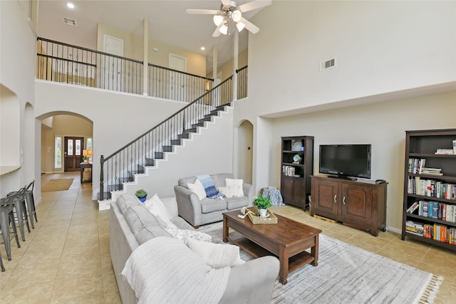 19538 Salt Grass Meadow Dr, Cypress, TX 77433 - living room featuring arched walkways, a high ceiling, light tile patterned floors, a ceiling fan, and stairway