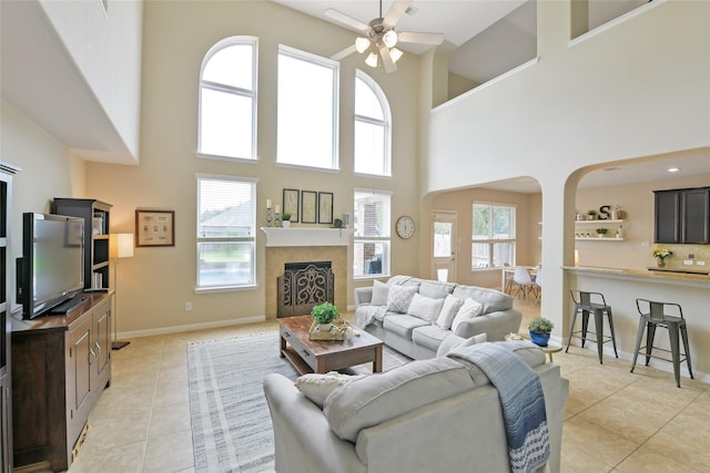 19538 Salt Grass Meadow Dr, Cypress, TX 77433 - living area featuring a towering ceiling, a ceiling fan, arched walkways, light tile patterned flooring, and a fireplace