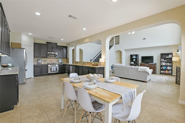 19538 Salt Grass Meadow Dr, Cypress, TX 77433 - dining space with arched walkways, light tile patterned floors, stairs, and recessed lighting