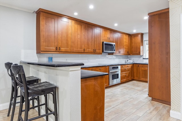 811 Lovett Blvd Unit 26, Houston, TX 77006 - kitchen with appliances with stainless steel finishes, a breakfast bar, brown cabinets, dark countertops, and recessed lighting