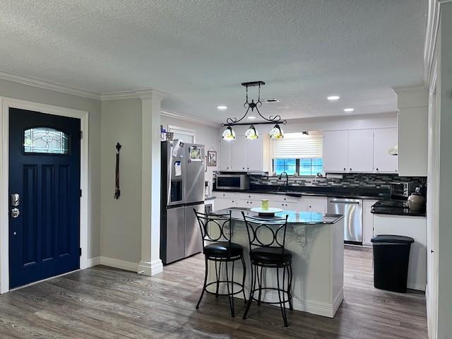 8594 Morgan Ln, Orange, TX 77632 - kitchen featuring appliances with stainless steel finishes, dark countertops, backsplash, a textured ceiling, and crown molding