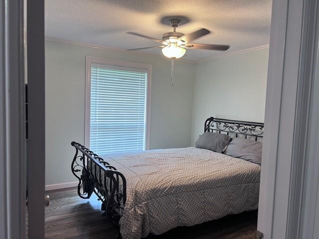 8594 Morgan Ln, Orange, TX 77632 - bedroom featuring dark wood-style floors, baseboards, crown molding, a textured ceiling, and a ceiling fan