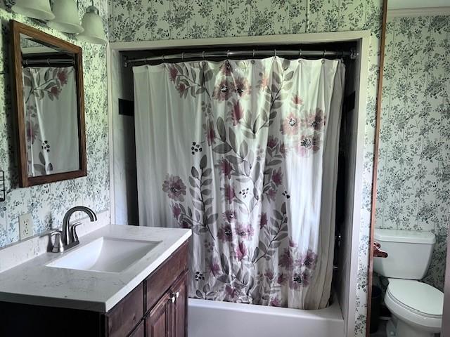 8594 Morgan Ln, Orange, TX 77632 - bathroom featuring wallpapered walls, vanity, toilet, and shower / bathtub combination with curtain