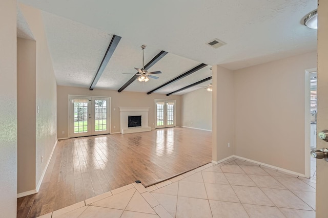 9519 Landry Blvd, Spring, TX 77379 - unfurnished living room featuring a ceiling fan, baseboards, beamed ceiling, a fireplace with raised hearth, and light tile patterned flooring