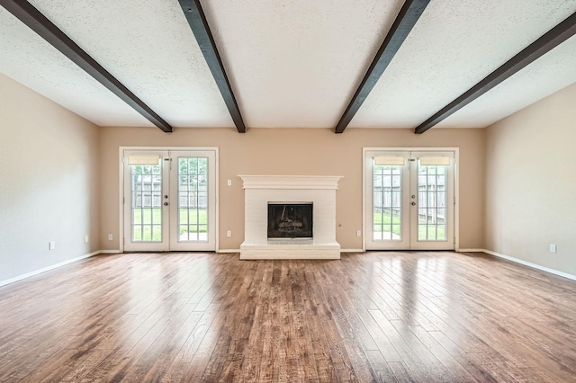 9519 Landry Blvd, Spring, TX 77379 - unfurnished living room featuring french doors, beamed ceiling, wood-type flooring, baseboards, and a textured ceiling