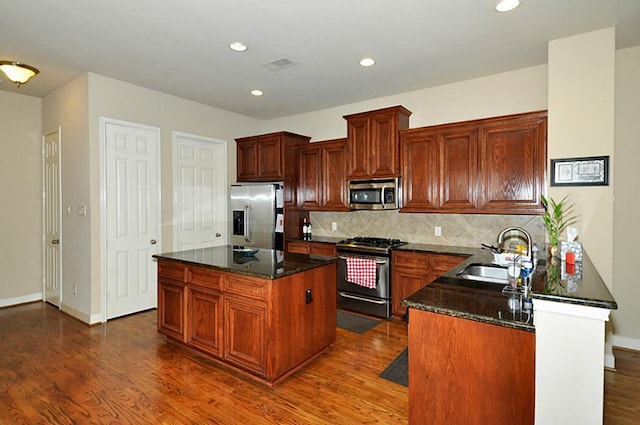 2366 Bastrop St, Houston, TX 77004 - kitchen featuring appliances with stainless steel finishes, a sink, dark wood-style flooring, backsplash, and dark stone countertops