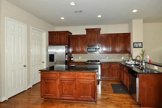 2366 Bastrop St, Houston, TX 77004 - kitchen with stainless steel appliances, a sink, dark stone countertops, dark wood-type flooring, and tasteful backsplash