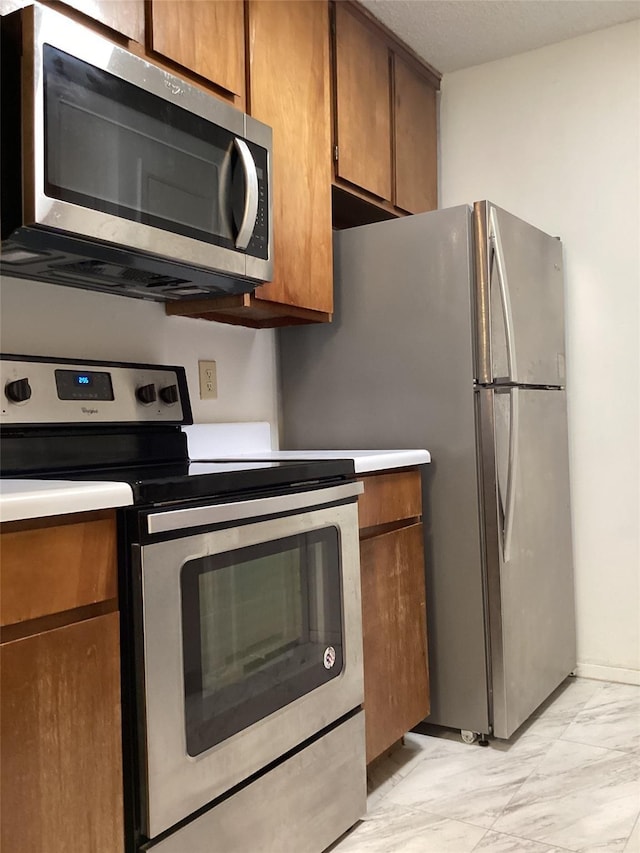 10049 Westpark Dr Unit 120, Houston, TX 77042 - kitchen featuring stainless steel appliances, light marble finish floors, light countertops, and brown cabinetry