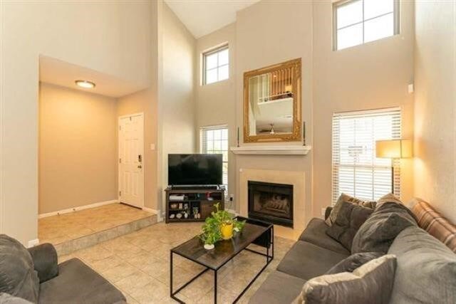 1620 Wellington Pl Unit 303, Beaumont, TX 77706 - living room with a towering ceiling, a fireplace, tile patterned floors, and baseboards