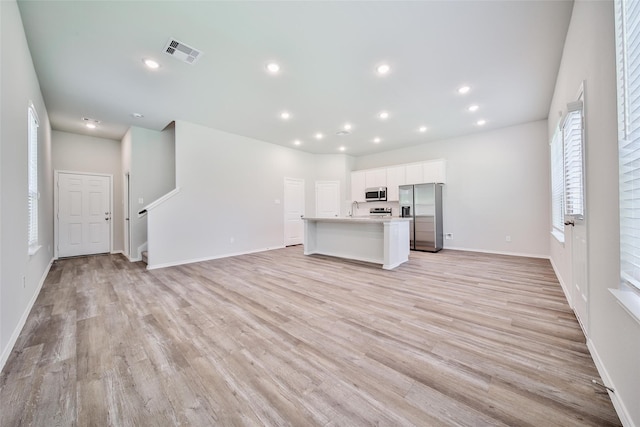 1452 Glenoaks Dr, Conroe, TX 77385 - unfurnished living room with light wood-type flooring, baseboards, recessed lighting, and stairs