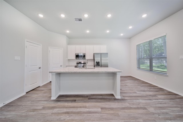 1452 Glenoaks Dr, Conroe, TX 77385 - kitchen with stainless steel appliances, an island with sink, white cabinets, light wood-type flooring, and recessed lighting