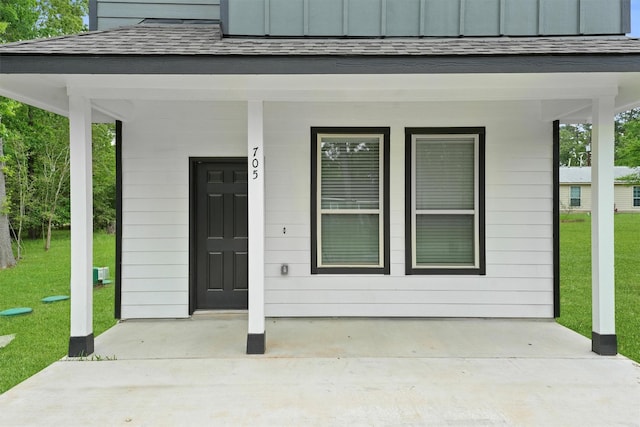 705 Little River Dr, Montgomery, TX 77316 - view of exterior entry with a yard, a shingled roof, and a porch