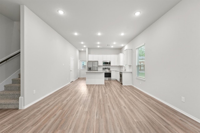 705 Little River Dr, Montgomery, TX 77316 - unfurnished living room with a sink, light wood-type flooring, stairs, baseboards, and recessed lighting