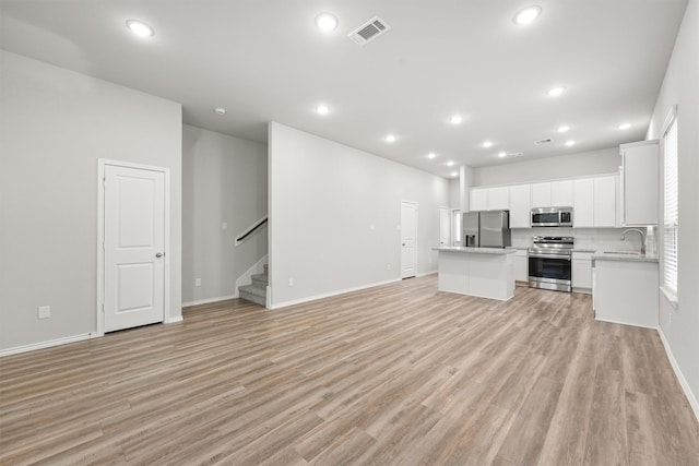 705 Little River Dr, Montgomery, TX 77316 - unfurnished living room with stairs, a sink, light wood finished floors, recessed lighting, and baseboards