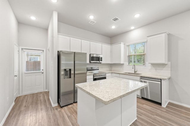 705 Little River Dr, Montgomery, TX 77316 - kitchen with stainless steel appliances, a sink, a kitchen island, decorative backsplash, and white cabinets