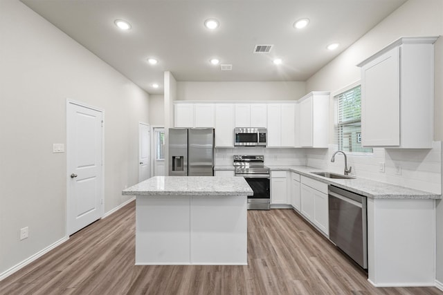 705 Little River Dr, Montgomery, TX 77316 - kitchen featuring appliances with stainless steel finishes, a sink, a kitchen island, tasteful backsplash, and light wood finished floors