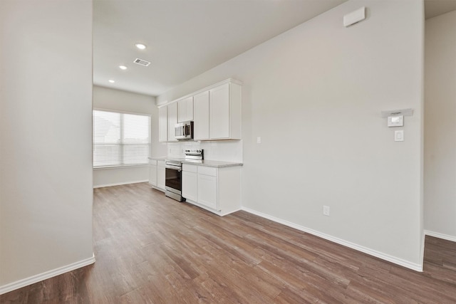 2116 Cedar Bend Dr, Conroe, TX 77306 - kitchen featuring appliances with stainless steel finishes, wood finished floors, baseboards, white cabinets, and recessed lighting
