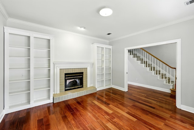 263 S Crimson Clover Ct, The Woodlands, TX 77381 - unfurnished living room with ornamental molding, wood finished floors, a brick fireplace, and stairway