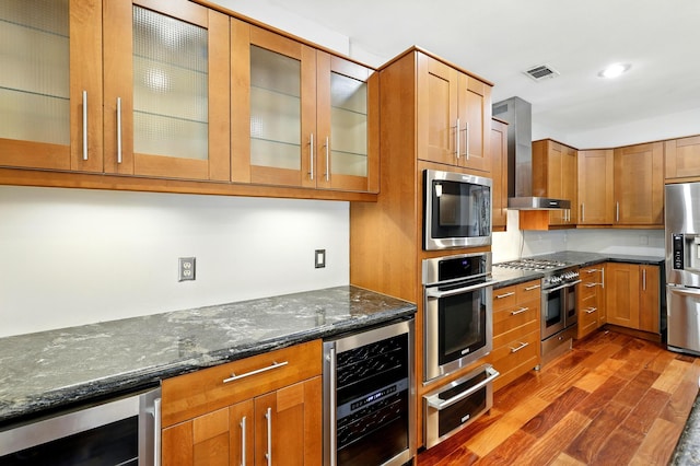 263 S Crimson Clover Ct, The Woodlands, TX 77381 - kitchen featuring beverage cooler, appliances with stainless steel finishes, wall chimney range hood, a warming drawer, and dark wood-style flooring