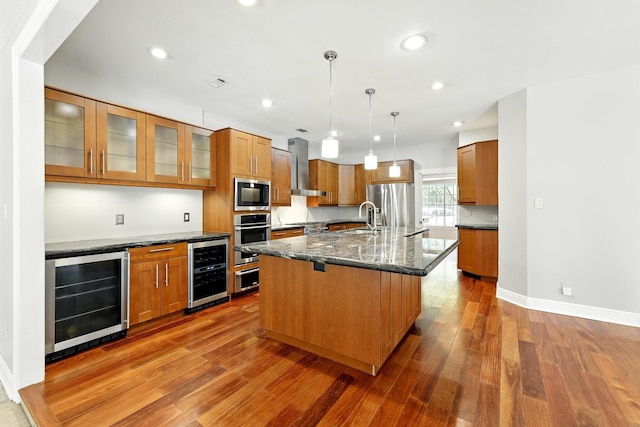 263 S Crimson Clover Ct, The Woodlands, TX 77381 - kitchen with beverage cooler, stainless steel appliances, wall chimney range hood, brown cabinets, and recessed lighting
