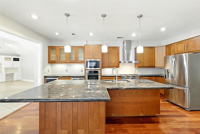 263 S Crimson Clover Ct, The Woodlands, TX 77381 - kitchen with stainless steel appliances, wall chimney range hood, recessed lighting, brown cabinetry, and wood finished floors